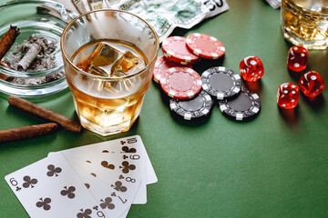 Glass of whiskey, cigar, playing cards and chips on green background