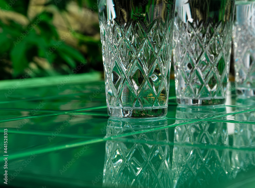 Wall mural Refreshing summer drinks in crystal glasses on green bar tile background reflection harsh shadow. Cold gin vodka cocktail for hot summer day. Non alcoholic soda clear water mint tonic. Party vacation