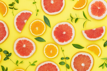 Summer bright background with oranges, grapefruits and green leaves on the yellow surface	
