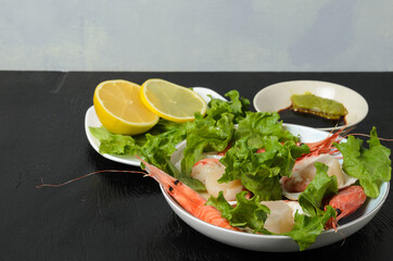 Natural raw scallop with boiled shrimp in the sink in a ceramic bowl with lettuce leaves and sauce...