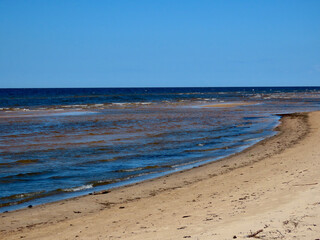 Baltic sea and sandy beach: blue sky and sea, white waves, yellow sand as copy space