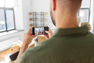 moving, people and real estate concept - man with smartphone taking picture of new home