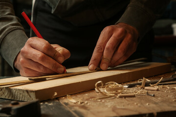 Obraz na płótnie Canvas Carpenter measuring and marking wood in workshop 