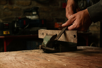 Man working with a piece of iron in mini table clamp	