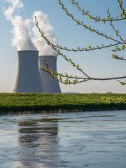 Branch with green leaves  against nuclear power plant.