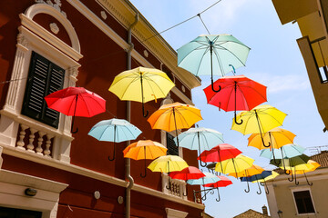 Fototapeta na wymiar Fröhliche Regenschirme im Sonnenlicht als Himmel einer Gasse am Mittelmeer