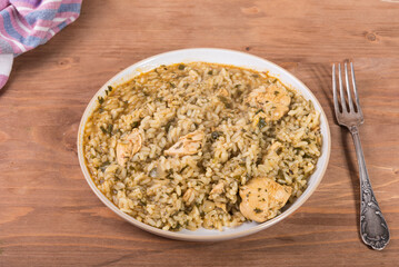 Italian risotto with chicken on a plate, top view, fork on the table next to the plate, rice pilaf with chicken