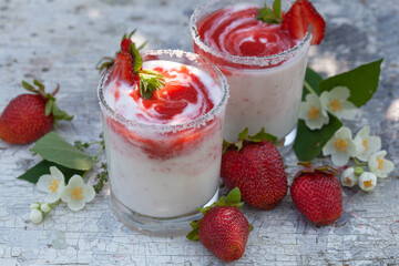 Two glasses of yogurt with strawberries on the table.