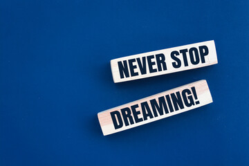 Never stop dreaming words printed on wooden blocks on blue. Positive thinking mindset concept