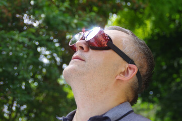 Man watching a solar eclipse phenomenon through safety glasses