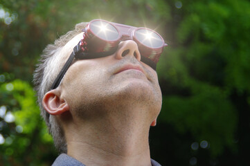 Man watching a solar eclipse phenomenon through safety glasses
