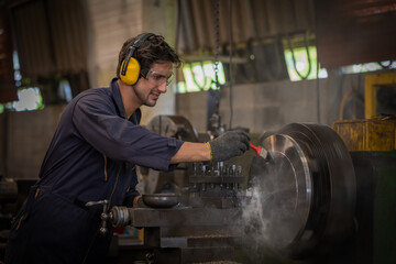 Industry worker wearing safety uniform used lubricant oil control operating lathe grinding machine...