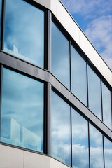 Architectural detail with large windows reflections of sky and sharp angles in modern design