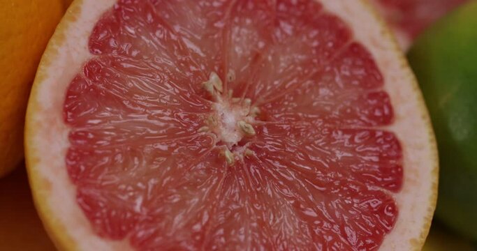 Close up of pink grapefruit halves and other citrous fruits in a large glass bowl. 