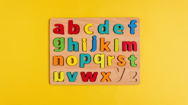 Letters of the English alphabet on a yellow background top view. Stop motion animation. Selective focus