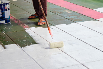 worker painting white color on the floor by roller paint