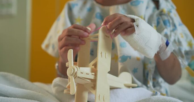 Sick girl playing toy airplane while stay in the hospital bed alone