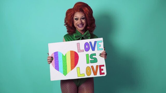 Happy drag queen celebrating gay pride holding banner with rainbow flag symbol of LGBTQ social movement	