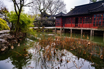 red wooden chinese pavilion near the water pond in the Suzhou garden at autumn season, interesting place to visit, travel, rest, relax, meditation
