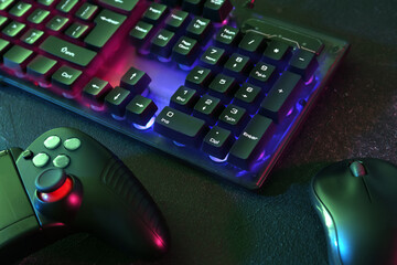 Modern RGB keyboard, mouse and video game controller on grey table, closeup