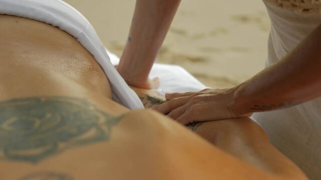 Hawaiian Lomi Lomi Massage By The Beach. Female Therapist Doing A Flowing Stroke On The Arm Of A Beautiful Woman. close up