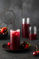 Fresh berries juce made with different berries cherry, strawberry and raspberry on dark background.
