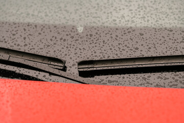 Automotive industry. Close up view of a pair of car wiper blades with small raindrops on window.