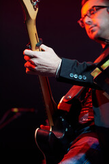 A male musician sings into a microphone and plays the guitar at a concert. Blurry motion.