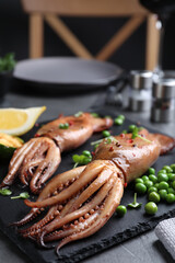 Tasty grilled squids served on black table, closeup