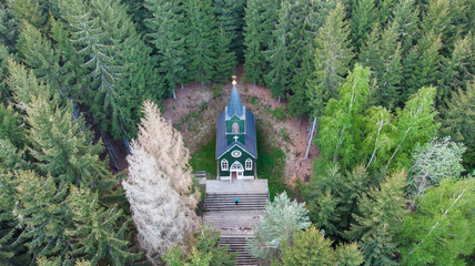 Aerial view of wooden rural chapel called Tichackova kaple in Broumovsko region,Czech republic.Catholic church in spring countryside.Religious meditation scenery.Pilgrimage place in forest.