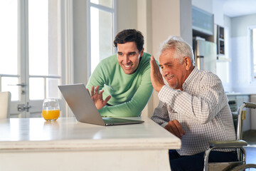 Fototapeta premium Father and son wave together while video chat on laptop