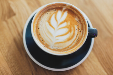 Tasty cappuccino in cup on wooden table
