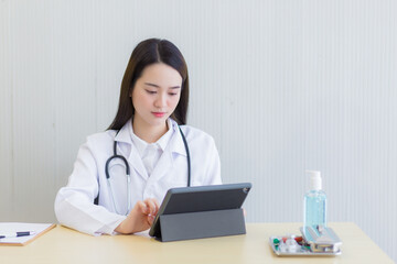 Coronavirus protection concept. Serious professional doctor wearing white coat and stethoscope holding modern touchscreen gadget using digital tablet computer at work.