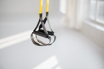 Suspension straps with handles for TRX training at white gym