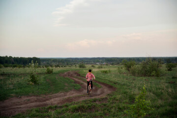 A boy in a plaid shirt rides a bicycle.