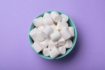 Delicious puffy marshmallows on lilac background, top view