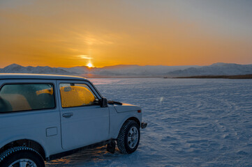sunset over the lake winter with a car