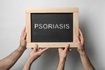 Men board with word PSORIASIS on light background, closeup