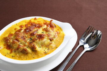 oven baked creamy cheese Japanese curry pasta with chicken in bowl western chef cuisine seafood menu in white and brown background