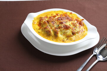 oven baked creamy cheese Japanese curry pasta with chicken in bowl western chef cuisine seafood menu in white and brown background