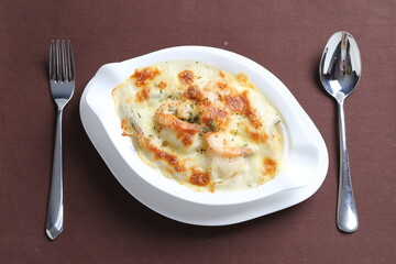 oven baked creamy cheese carbonara pasta with fresh big prawn in bowl western chef cuisine seafood menu in white and brown background