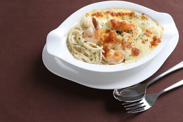 oven baked creamy cheese carbonara pasta with fresh big prawn in bowl western chef cuisine seafood menu in white and brown background