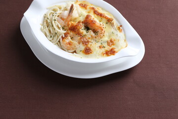 oven baked creamy cheese cabonala pasta with fresh big prawn in bowl western chef cuisine seafood menu in white and brown background