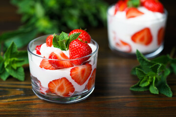 Whipped cream and strawberries served in a glass. Dark wooden table, high resolution