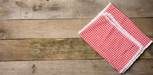 folded red and white cotton kitchen napkin on a wooden gray background