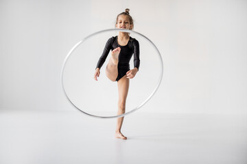 Little girl practising rhythmic gymnastic with a ring at white room. Children's gymnastics and...