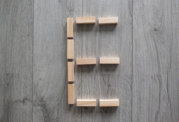 Naklejka na ściany i meble letter E natural wooden blocks on floor alphabet lettering