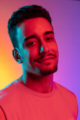 Close-up portrait of Latina young man isolated on gradient yellow purple background in neon light....
