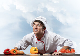 Young smiling chef standing near cooking table
