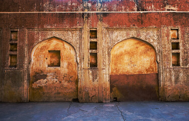Front view of a grunge, weathered wall of ancient fort with arch design. Details of ruins from an...